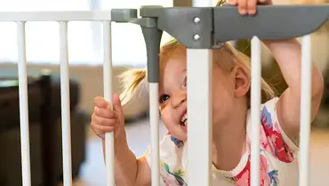 Toddler looking through a baby gate.