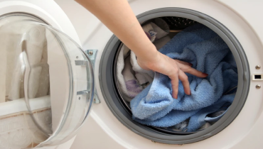 Hand placing towels in dryer.