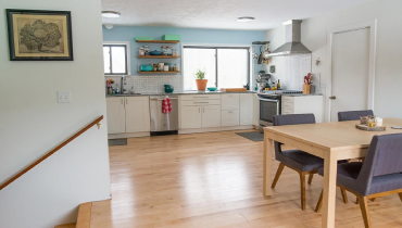 White modern eat-in kitchen with stairs leading down.