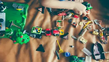 Child playing with toys scattered on the ground.